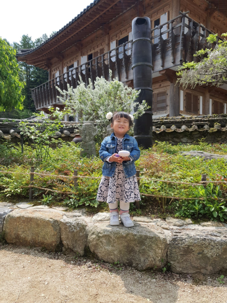 Child posing in front of a traditional hanok at Nak Seon Jae