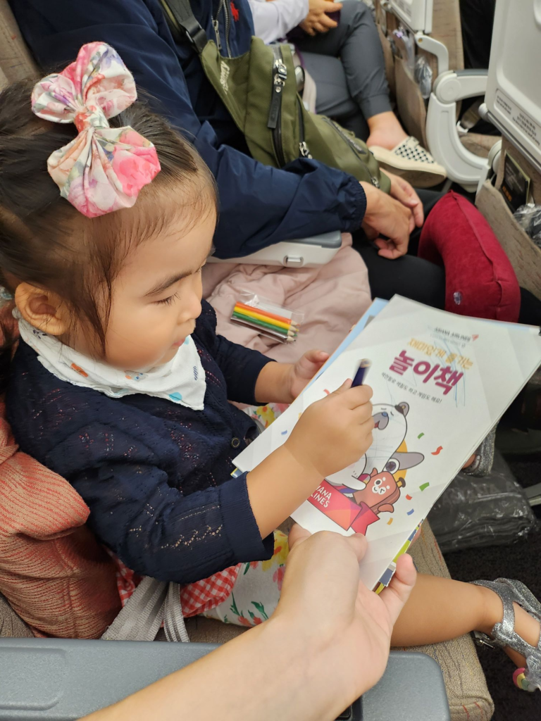child playing quietly with coloring book on a plane