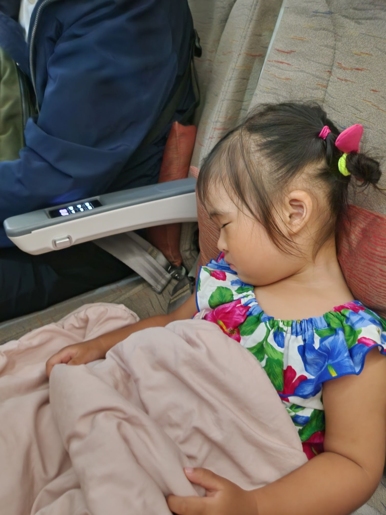 toddler sleeping on an airplane seat during a night flight