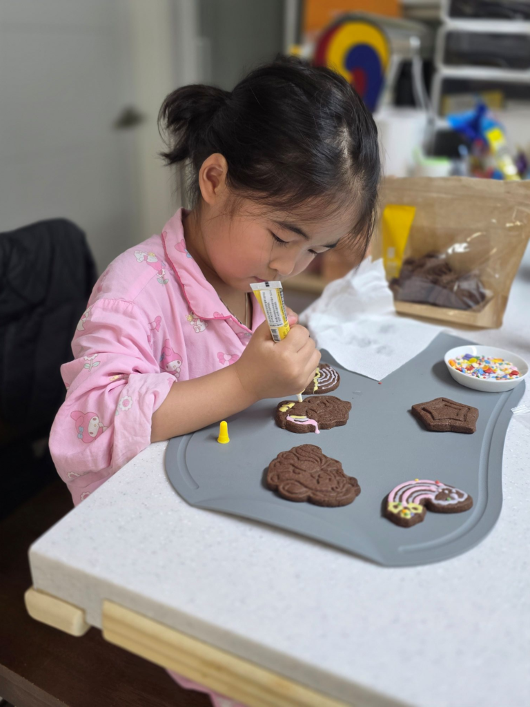 child concentrating while decorating cookies